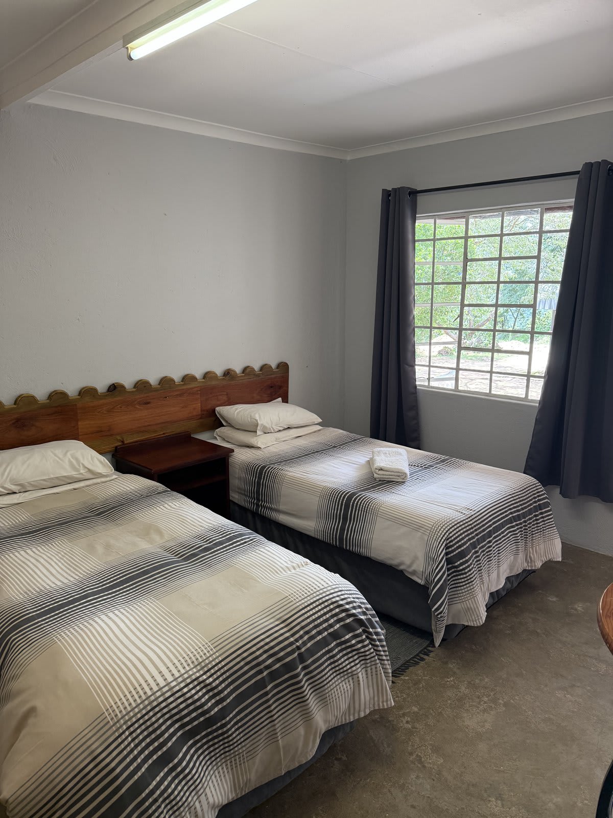 A twin room at Kanaan — soft linen, scalloped wooden headboards, the kind of room you come back to between days out.